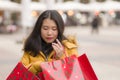 Asian girl enjoying Christmas shopping - young happy and beautiful Japanese woman holding red shopping bag buying presents at Royalty Free Stock Photo