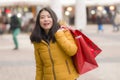 Asian girl enjoying Christmas shopping - young happy and beautiful Korean woman holding red shopping bag buying presents at street Royalty Free Stock Photo