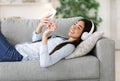 Asian girl enjoying listening music on smartphone with wireless headphones at home Royalty Free Stock Photo