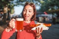 Asian girl enjoys snacking on junk food - hot dog with fried sausage and beer