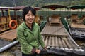 Asian girl ferryman moors bamboo raft, and smiles, Guangxi, China.