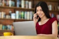 Asian Girl Freelancer Talking On Cellphone While Working On Laptop In Cafe Royalty Free Stock Photo