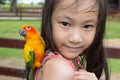 Asian girl has a parrot perched on her shoulder,child happy with the bird in the zoo Royalty Free Stock Photo