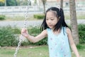 Asian girl holding chain swing in the park.