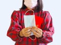 Asian girl holding face mask and red evelope angpao for gift on Chinese new year holiday