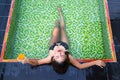 Asian girl holding glass of orange juice in her hands lying in the swimming pool Royalty Free Stock Photo