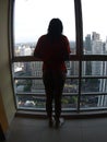 asian girl indoors by window looking out city view daytime