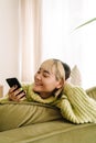 Asian girl laughing and talking on cellphone while resting on sofa