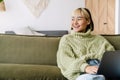 Asian girl laughing and working with laptop while resting on sofa Royalty Free Stock Photo