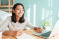 Asian girl learning online via the internet tutor on a laptop computer, Asia child is studying while sitting Interior at home