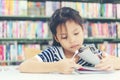 Asian girl in library reading something in a book and choosing a book in a library. Royalty Free Stock Photo