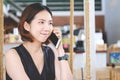 Asian girl listening to a call on her mobile phone, Young beautiful thai woman talking with smiley face in modern cafe Royalty Free Stock Photo
