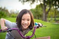 Asian girl looking at camera, smiling with a cute on bicycle in the outdoor park,child exercise in nature in the morning,healthy Royalty Free Stock Photo