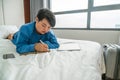 Asian girl lying on bed and writing notes Royalty Free Stock Photo