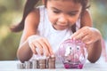 Asian girl making stacks of coins and putting money into piggy bank Royalty Free Stock Photo