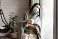 Asian girl in medical face mask, yearning go outside, being sick with covid 19 and staying on self quarantine in her