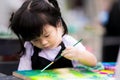 Asian girl paint art on canvas. Happy children are learning art. Cute children wear an apron during watercolor lessons.