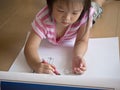 Asian girl Painting crayon on large sheets of paper On the floor