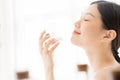 Asian girl with perfume, young woman applying perfume on her wrist and smelling.