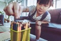 Asian girl picking up colorful crayon pencil on the table for creative drawing at home, for Creative education concept Royalty Free Stock Photo