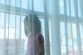 Asian girl playing behind the sheer curtain by big window with e