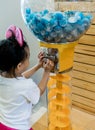 Asian girl playing lucky draw from ball vending machine.