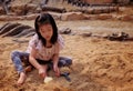 An Asian girl playing in a sandbox with a modeled dinosaur fossil Royalty Free Stock Photo