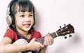 Asian girl is practicing guitar and wearing headphone. Royalty Free Stock Photo