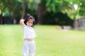 Asian girl pretends to throw an orange ball in her hand behind her head. Children play on the bright green lawn. Kids exercise.