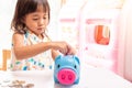 Asian girl putting coin in the piggy bank for saving money. Selective focus of child hand Royalty Free Stock Photo