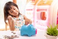 Asian girl putting coin in the piggy bank for saving money. Selective focus of child hand Royalty Free Stock Photo