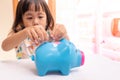 Asian girl putting coin in the piggy bank for saving money. Selective focus of child hand Royalty Free Stock Photo