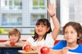 Asian girl raising hand in multi ethnic elementary classroom Royalty Free Stock Photo