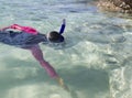 Asian girl reaches for fish while snorkeling