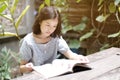 Asian girl reading a book in the backyard garden