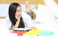 Asian girl reading a book in bed, lying on her stomach smiling h Royalty Free Stock Photo