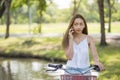 Asian girl ride bicycle and talk on smartphone Royalty Free Stock Photo