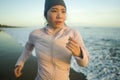 Asian girl running on the beach - young attractive and happy Korean woman doing jogging workout at beautiful beach enjoying Royalty Free Stock Photo