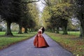 Asian Girl posing down the centre of an Avenue of autumn trees Elephant Grass field