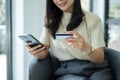 Asian girl shopping online holding credit and using smartphone enter their card number in the mobile phone app to purchase and Royalty Free Stock Photo