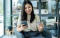 Asian girl shopping online holding credit and using smartphone enter their card number in the mobile phone app to purchase and Royalty Free Stock Photo