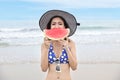 Asian girl short hairs and sexy body who wearing blue bikini and nice hat. She holding and eating watermelon with a happy smiling Royalty Free Stock Photo