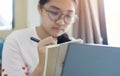 Asian girl sit in living room study on laptop making notes, concentrated young woman work on computer write in notebook Royalty Free Stock Photo