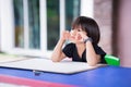 Asian girl sits with her arms on her chin while waiting to study art. Child is sitting blankly. Kid gets bored while waiting. Royalty Free Stock Photo