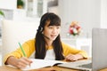 Asian girl sitting at table and using laptop during online lessons Royalty Free Stock Photo