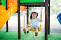 Asian girl smile play swing on school or kindergarten yard or playground. Healthy summer activity for children. Little asian girl Royalty Free Stock Photo