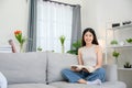 asian girl Smiling and looking at camera at home sitting and reading a book on the sofa in the living room Young woman relaxing in Royalty Free Stock Photo