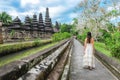 Asian girl standing front of the gate of Pura Taman Ayun Temple in Bali, Indonesia