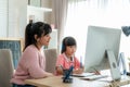 Asian girl student with mother video conference e-learning with teacher on computer in living room at home. Homeschooling and Royalty Free Stock Photo