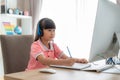 Asian girl student video conference e-learning with teacher on computer in living room at home. Homeschooling and distance Royalty Free Stock Photo